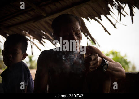 Mentawai uomo di fumare un tipico sigaro locale Foto Stock