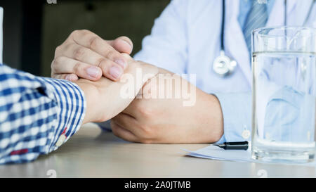 Medico maschio tenendo mano del paziente, confortando paziente che è in ambulanza, aiutando concetto. Foto Stock