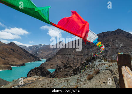 Colorati bandiere di preghiera vola alto oltre il paesaggio tibetano. Foto Stock