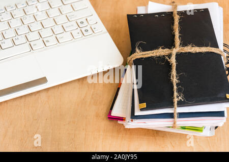 La risma di buste legato con corda e tastiera portatile su sfondo di legno. Sul posto di lavoro. Copia dello spazio. Foto Stock