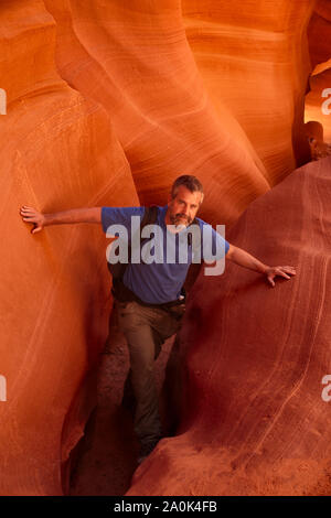 Uomo caucasico con i capelli grigi e la barba escursioni attraverso uno slot Canyon in Arizona su un giorno di estate, Pagina, AZ, Stati Uniti d'America Foto Stock