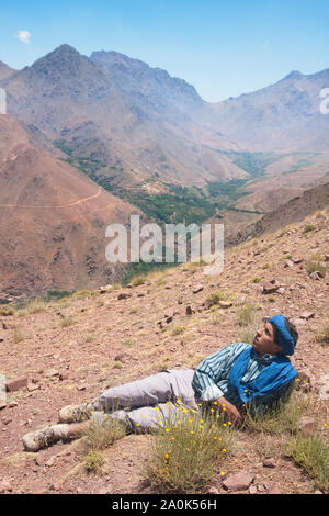 Uomo marocchino nel suo 20's pause di riposo a Tizi 'n Tamer, 2200 metri di altezza in Ait Mizane valley, Alto Atlante, Marocco Foto Stock