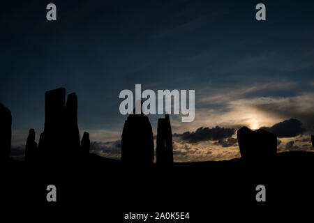 Set di sole in una pietra intagliata profilarsi nel tramonto al Callanish Standing Stones, isola di Lewis, Ebridi Esterne, Scotland, Regno Unito, Europa Foto Stock