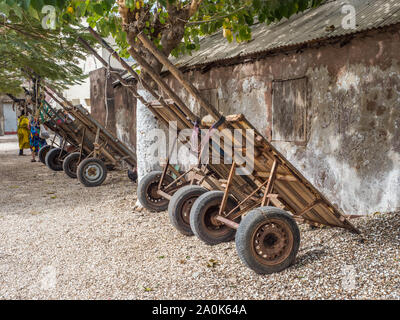 Joal-Fadiouth, Senegal - Gennaio 24, 2019: alcuni carrelli sono in piedi accanto all'edificio dell'isola Joal-Fadiouth. Città e comune è in Thiès Foto Stock