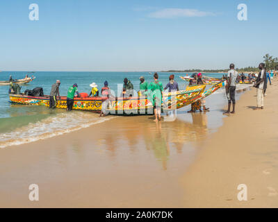 Nianing, Senegal - Gennaio 2, 2019: i pescatori la raccolta di pesce di legno colorato barca fisher permanente sulla spiaggia. Africa Foto Stock