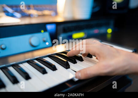 Mano del pianista premendo uno dei tasti della tastiera di pianoforte durante la registrazione di musica Foto Stock