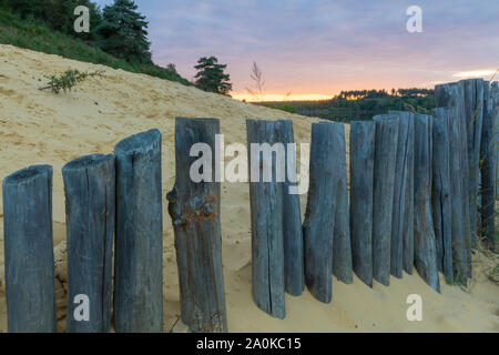 Tramonto al Mechelse Heide (Inglese prato Mechelse) con una vista panoramica di essere sulla spiaggia con sabbia e pali in legno Foto Stock