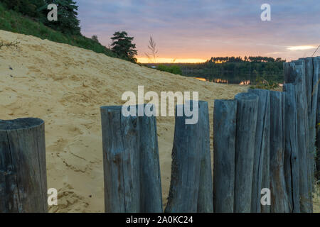 Tramonto al Mechelse Heide (Inglese prato Mechelse) con una vista panoramica di essere sulla spiaggia con sabbia e pali in legno Foto Stock