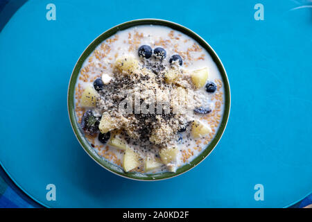 Una sana colazione a base di cereali ciotola con fresco tritato mirtilli melone semi di chia vista da sopra su sfondo blu in Londra England Regno Unito KATHY DEWITT Foto Stock