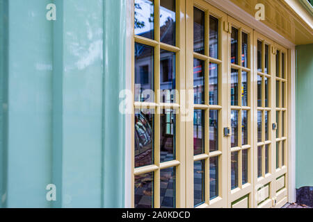 Facciata colorata pastello con pareti di colore verde e giallo pastello porte finestre e riflessi nelle finestre di vetro nel pastello porte verniciate Foto Stock