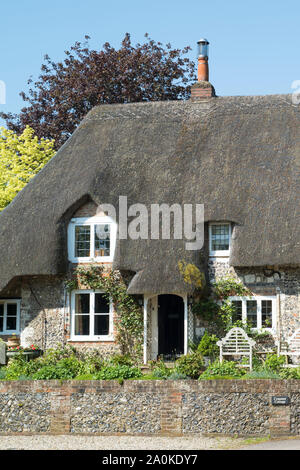 Inglese tipica pietra costruito cottage con tetto in paglia in mattoni e pietra focaia costruzione tetto, ricoprendo di paglia, camini in Ramsbury, Wiltshire, Regno Unito Foto Stock