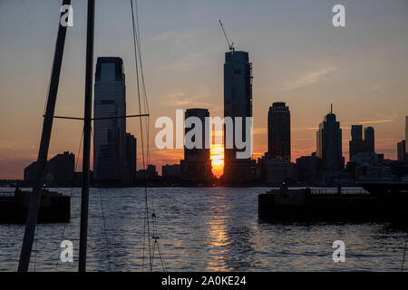 Il sole tramonta in tra due edifici in Jersey City è visto dal marina di Battery Park City Esplanade a New York City il 7 settembre 3, 2019. (Foto: Foto Stock