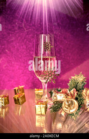 Decorazione di natale e bicchieri da champagne su sfondo viola con un raggio di luce sulla parte superiore Foto Stock