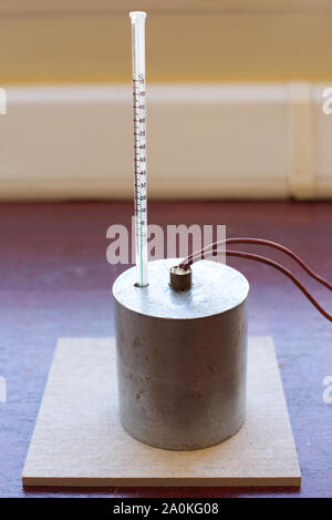 Capacità di calore specifico di esperimento di alluminio impostare senza isolamento. Il blocco di alluminio con un riscaldatore ad immersione e termometro su un tappetino resistente al calore Foto Stock