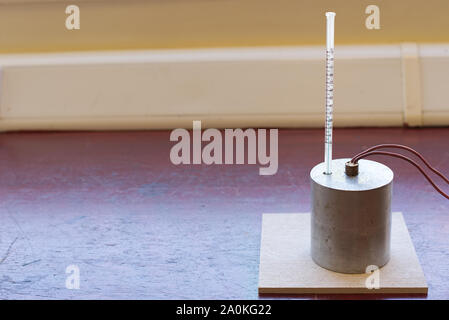 Capacità di calore specifico di esperimento di alluminio impostare senza isolamento. Il blocco di alluminio con un riscaldatore ad immersione e termometro su un tappetino resistente al calore Foto Stock
