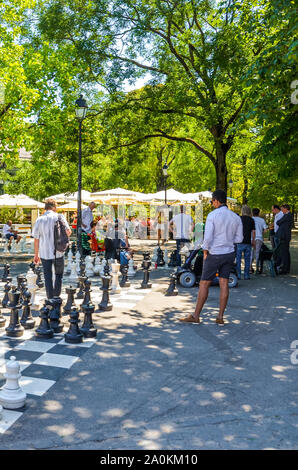 Ginevra, Svizzera - Luglio 19, 2019: persone che giocano a scacchi all'aperto Gioco con scacchi giganti figure nel Parc Des Bastions. Scacchi grandi pannelli sono situati all'ingresso del parco nel centro della citta'. Foto Stock