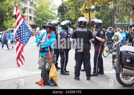 Un nativo americano man tenendo un capovolto bandiera accanto alla polizia presso il clima sciopero nel rally di Eugene, Oregon, Stati Uniti d'America. Foto Stock