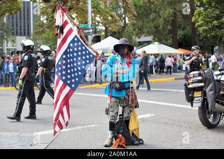 Un nativo americano man tenendo un capovolto bandiera accanto alla polizia presso il clima sciopero nel rally di Eugene, Oregon, Stati Uniti d'America. Foto Stock