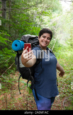 Felice guardando la millenaria pone per un selfie mentre mostra il camping Foto Stock