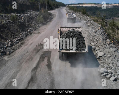 Enorme sulla strada di scarico industriale carrello in una cava di pietra caricato il trasporto di marmo o granito sparato da un drone Foto Stock