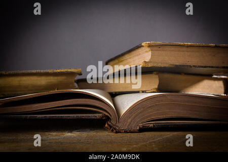 Pile di libri su una tabella su sfondo nero Foto Stock