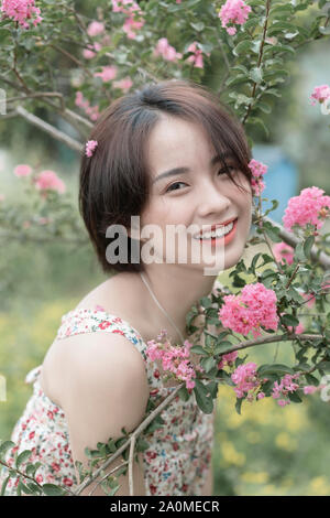 Bella ragazza dal rosa coriandoli giardino, bambina indossa un simpatico e bel vestito Foto Stock