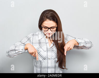 Sorridente bella donna d'affari di successo in bicchieri puntando le dita verso il basso. Closeup ritratto Foto Stock