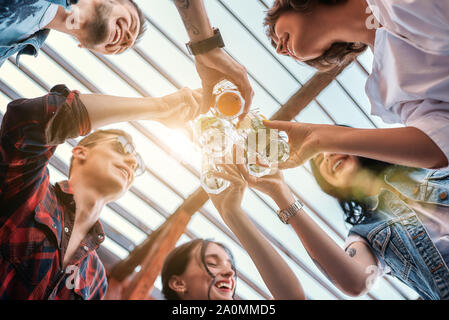 Avendo divertimento. Giovane gente allegra in chat e bere un cocktail seduti sul tetto. Il concetto di amicizia. Parte contraente Foto Stock