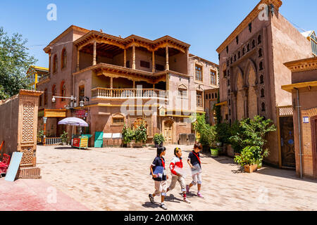 Kashgar rinnovato Città Vecchia Scuola di tre bambini sono a piedi giù per la strada su una soleggiata cielo blu giorno Foto Stock