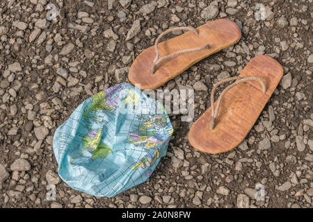 Indossato hippy flipflops & globo sgonfiato sulla superficie di scandole. Metafora terra piatta, flat earthers, teorie cospirative, piano terra prove, pseudoscience Foto Stock