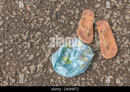 Indossato hippy flipflops & globo sgonfiato sulla superficie di scandole. Metafora terra piatta, flat earthers, teorie cospirative, piano terra prove, pseudoscience Foto Stock