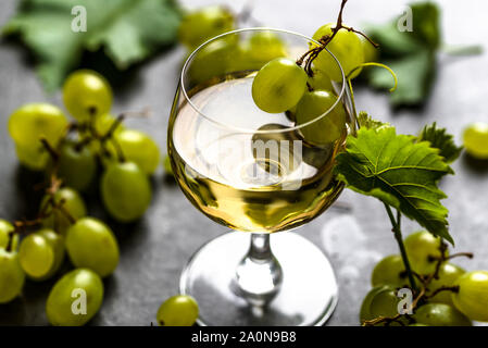 Un bicchiere di vino e di uve bianche appena raccolto in cantina Foto Stock