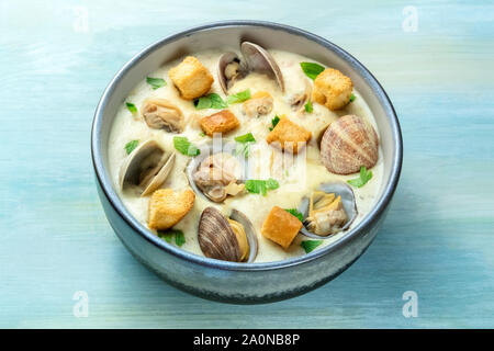 Clam Chowder, decorate con prezzemolo fresco e crostini, su uno sfondo blu Foto Stock