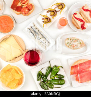 Tapas spagnoli, overhead square shot. Vino, sardine, insalata russa, padron peperoni, jamon e altri snack, ripresa dall'alto su sfondo bianco Foto Stock
