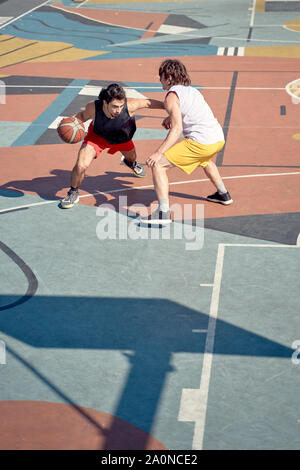 Top visualizza immagine di due giovani sportivi giocare a basket sul parco giochi in mattina sul giorno di estate Foto Stock