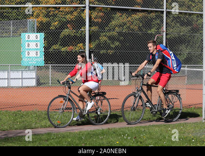 Coppia giovane in bicicletta tra le corti di tennis club Foto Stock