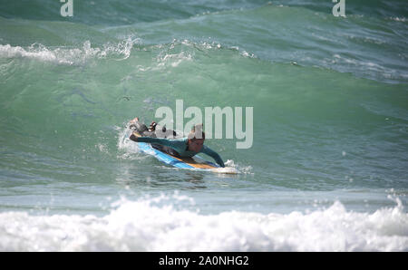 Un surfista nel mare di Boscombe beach vicino a Bournemouth, come le temperature sono attesi per volare a 26C in alcune parti del paese questo fine settimana. Foto Stock