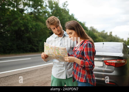 Auto turisti in cerca sulla mappa, lo spostamento su strada Foto Stock