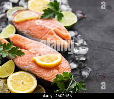 Materie filetti di salmone e gli ingredienti su un nero ardesia board Foto Stock