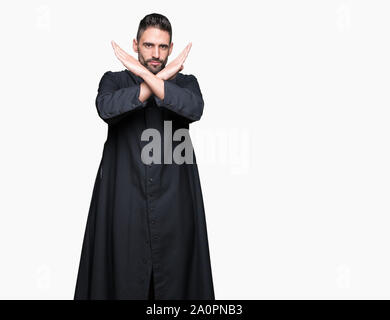 Giovane sacerdote cristiano su sfondo isolato rifiuto espressione bracci di incrocio facendo segno negativo, volto arrabbiato Foto Stock