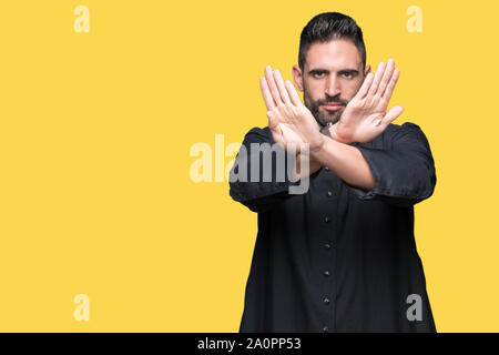 Giovane sacerdote cristiano su sfondo isolato rifiuto espressione bracci di attraversamento e di palme facendo segno negativo, volto arrabbiato Foto Stock