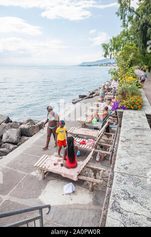 Comunità multiculturale a prendere il sole sulla spiaggia lungo il lago di Ginevra e da Montreux Riviera lungomare di Montreux, Vaud, Svizzera Foto Stock