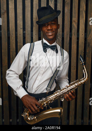 Nero sorridente musicista jazz pone con sassofono Foto Stock