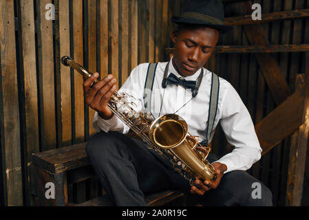 Nero musicista jazz seduto con il sassofono Foto Stock