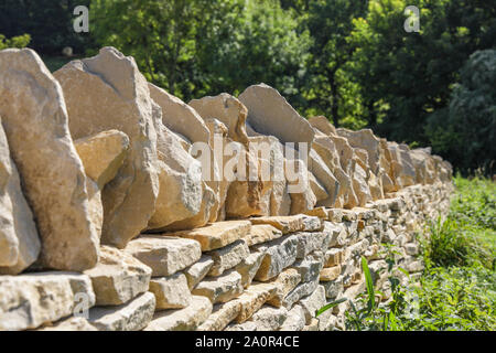 Un Cotswold secco muro di pietra nel processo di costruzione. Un paesaggio tradizionale artigianale specialità Foto Stock