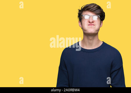 Giovane uomo bello con gli occhiali su sfondo isolato puffing guance con faccia buffa. Bocca gonfiato con aria, crazy espressione. Foto Stock
