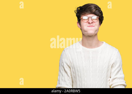 Giovane uomo bello con gli occhiali su sfondo isolato puffing guance con faccia buffa. Bocca gonfiato con aria, crazy espressione. Foto Stock