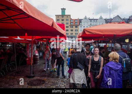 Giornata di pioggia nel mercato del pesce di Bergen, con la folla di turisti che vagano Foto Stock