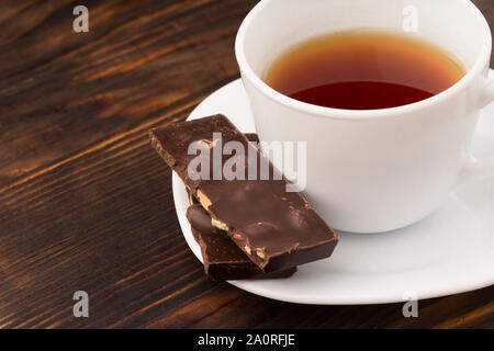 Tazza di tè con il cioccolato su un tavolo di legno. Foto Stock