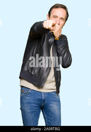 La mezza età uomo bello indossare nero giacca di pelle di ridere di voi, rivolta verso la telecamera con il dito la mano sulla bocca, vergogna expression Foto Stock